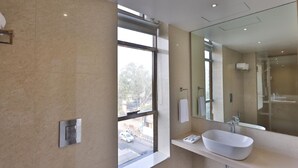 Un baño moderno con un ventanal grande, un lavabo blanco y un espejo.