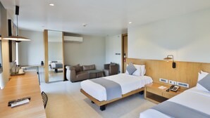 Una habitación de hotel moderna con una cama, un sofá, una mesita y un escritorio con teléfono.