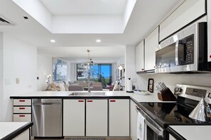 A modern kitchen with a central island, stainless steel appliances, and a view to the outside. - Beachview 2/2 condo, Pool, Beach (Longboat Key)