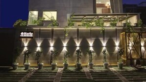 A multi-story hotel with illuminated signage and windows, surrounded by potted plants.