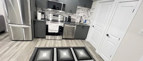 A modern kitchen with stainless steel appliances, a microwave, and a tiled backsplash.