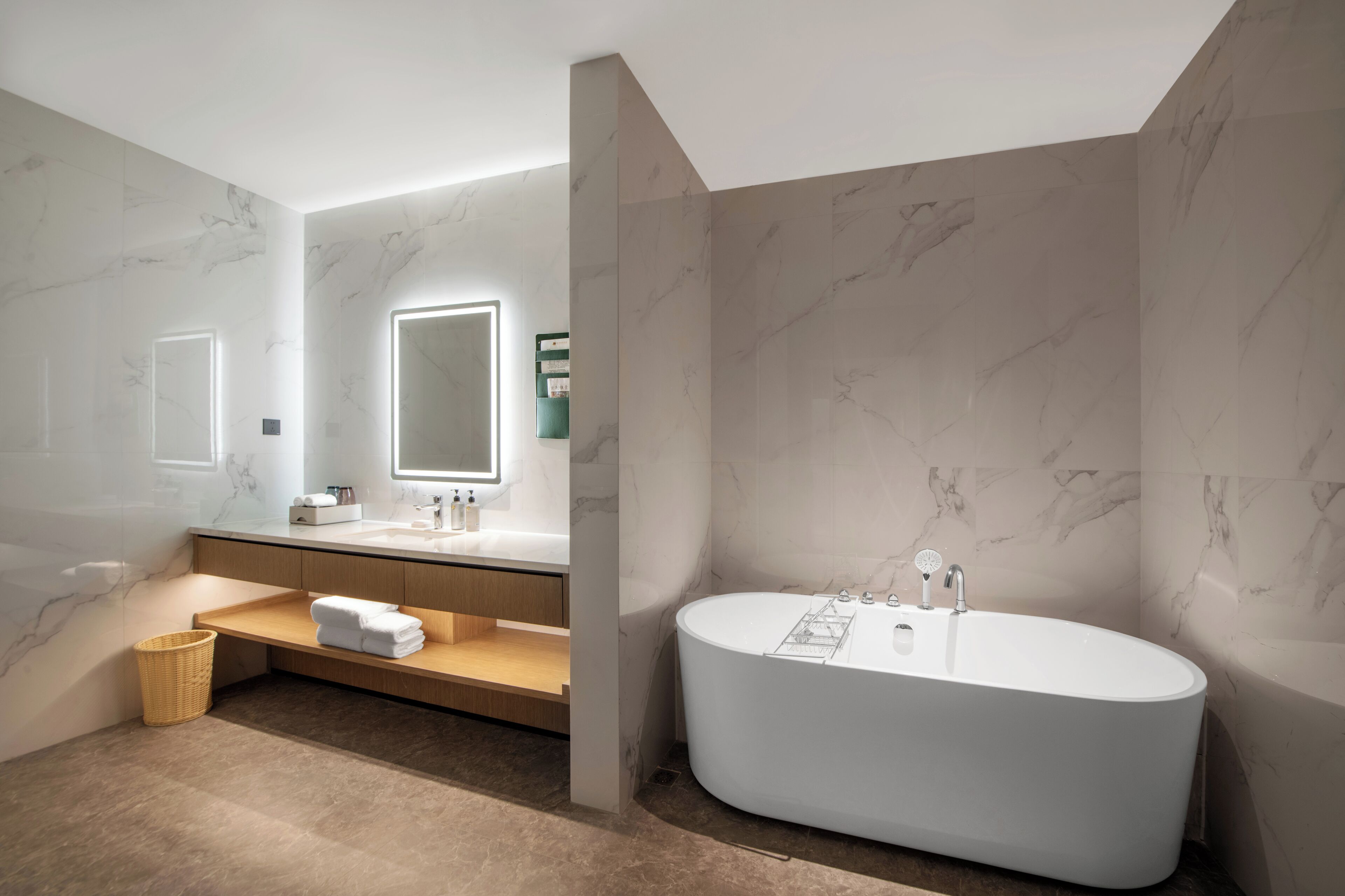 A modern bathroom with a freestanding bathtub, marble walls, and a vanity with a mirror.