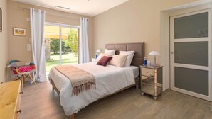 Quarto com cama, mesa de cabeceira, abajur e vista para o exterior.