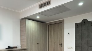 Ein modernes Zimmer mit integriertem Kleiderschrank, einer Bank und einem kleinen Tisch mit Telefon und Glasflaschen.
