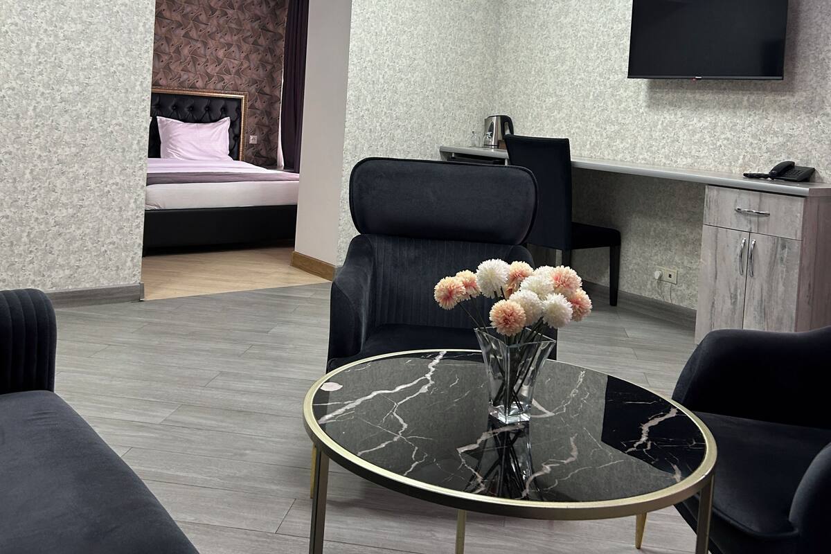 Una habitación de hotel moderna con cama, zona de estar con mesa, televisor y escritorio.