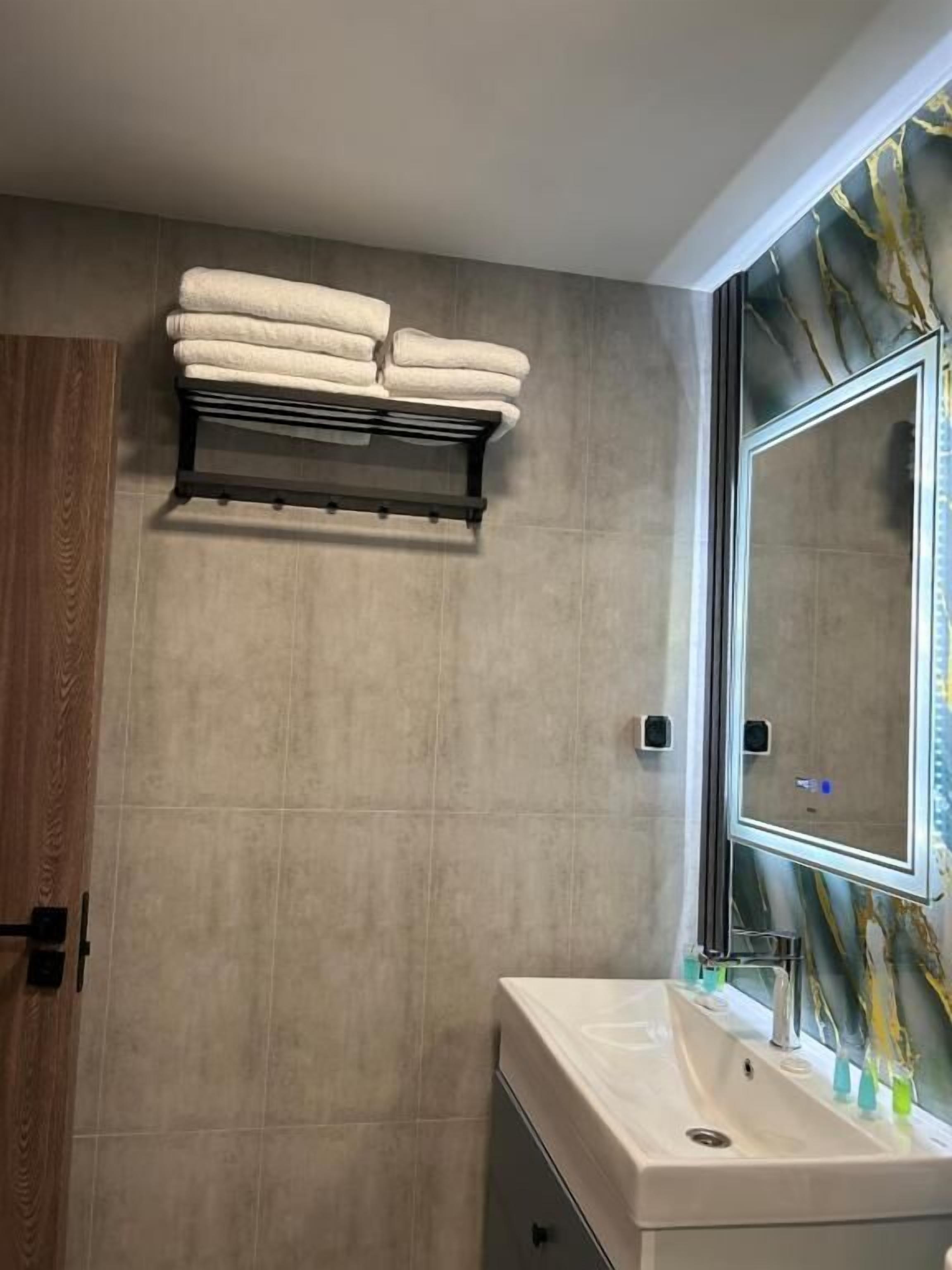 Un baño con un espejo grande, un lavabo y un perchero para toallas.