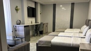 Ein modernes Hotelzimmer mit einer Couch, zwei Betten, einem Schreibtisch und einem Fernseher.