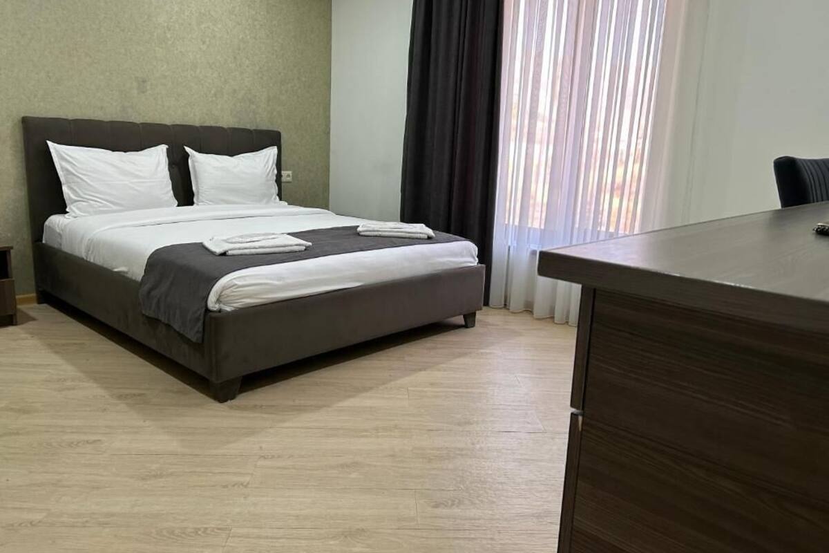 Una habitación de hotel con cama, escritorio y ventana con cortinas.