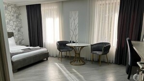 Ein Hotelzimmer mit einem Bett, zwei Sesseln, einem runden Tisch und einer dekorativen Wandverkleidung.