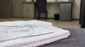 Ein Schlafzimmer mit einem Bett, einem Schreibtisch, einem Stuhl, einem Fernseher und einem kleinen Kühlschrank.