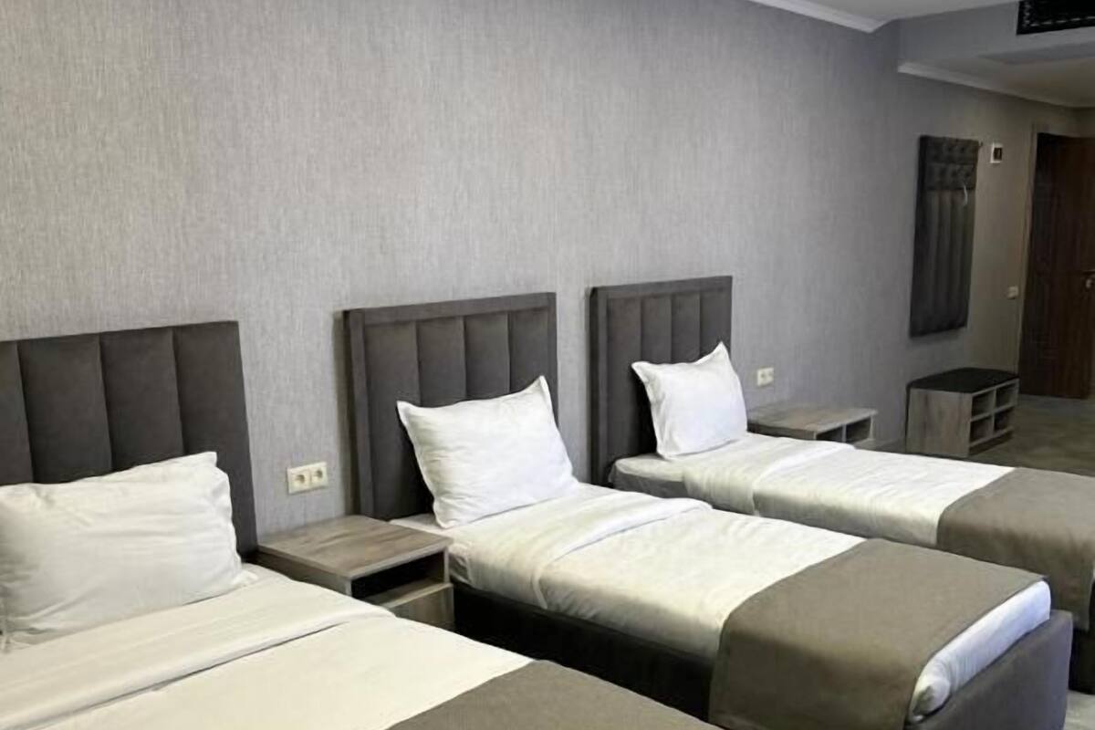 Una habitación de hotel con tres camas, un escritorio pequeño y un armario.