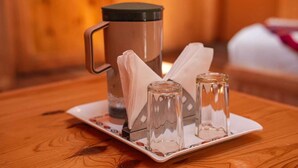 Et træbord med kaffepotte, serviet og to glas.