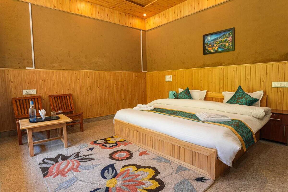 A wooden-paneled room with a bed, a desk, and a chair.
