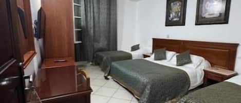 Habitación de hotel con dos camas, un escritorio, una silla, un armario y baño.