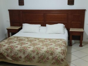 A bed with a floral bedspread, wooden headboard, and two nightstands with lamps. - Hotel sidi thameur (Algiers)