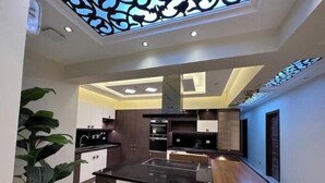 A modern kitchen with a central island, dark cabinetry, and a skylight. - Luxury Dreamland Retreat – Spacious Pool Stay Near the Pyramids (Giza Governorate)