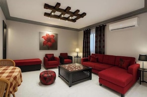 A modern living room with a red sofa, a coffee table, and a red armchair. - Pool View Villa Apartment – Private Garden Escape in Dreamland (Giza Governorate)