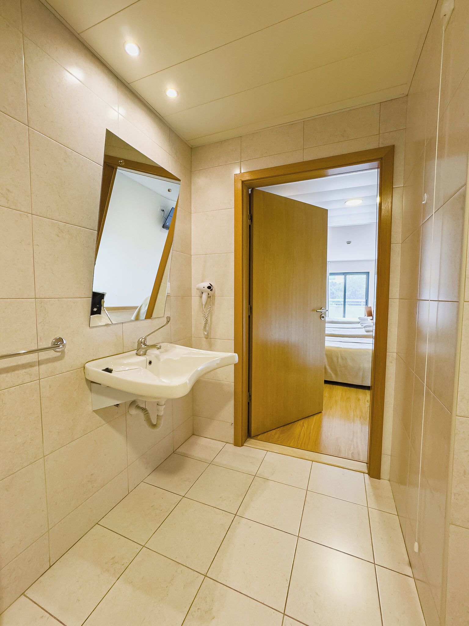 Een moderne badkamer met een wastafel, spiegel en haardroger.