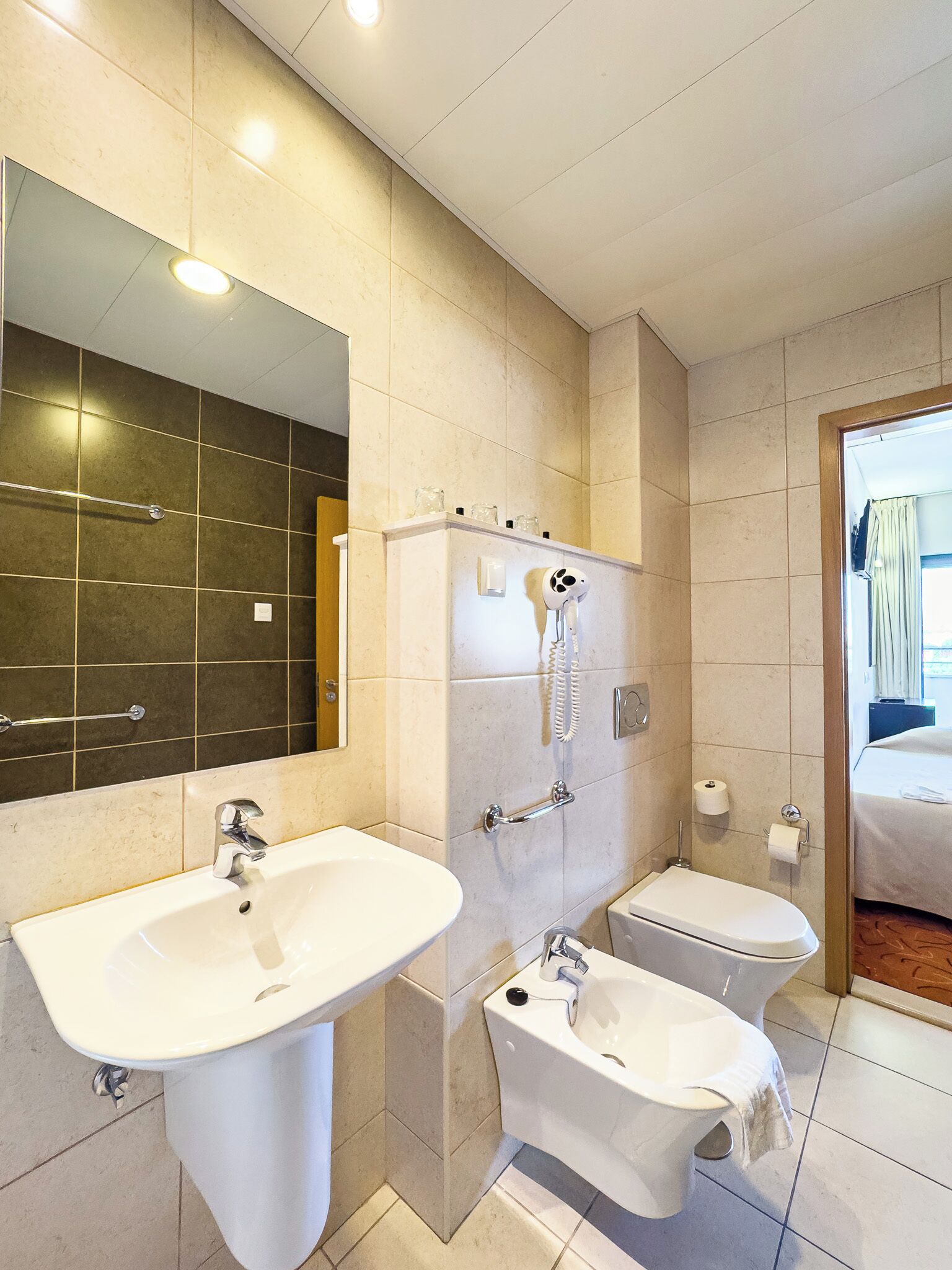 A modern bathroom with two sinks, a shower, and a toilet.