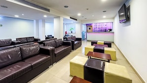 Eine Hotlellobby mit Ledersofas, einer Bar und einem an der Wand befestigten Fernseher.