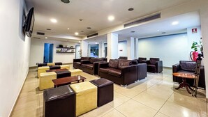 Eine Hotelhalle mit Ledersofas, Holztischen und einer Rezeption.
