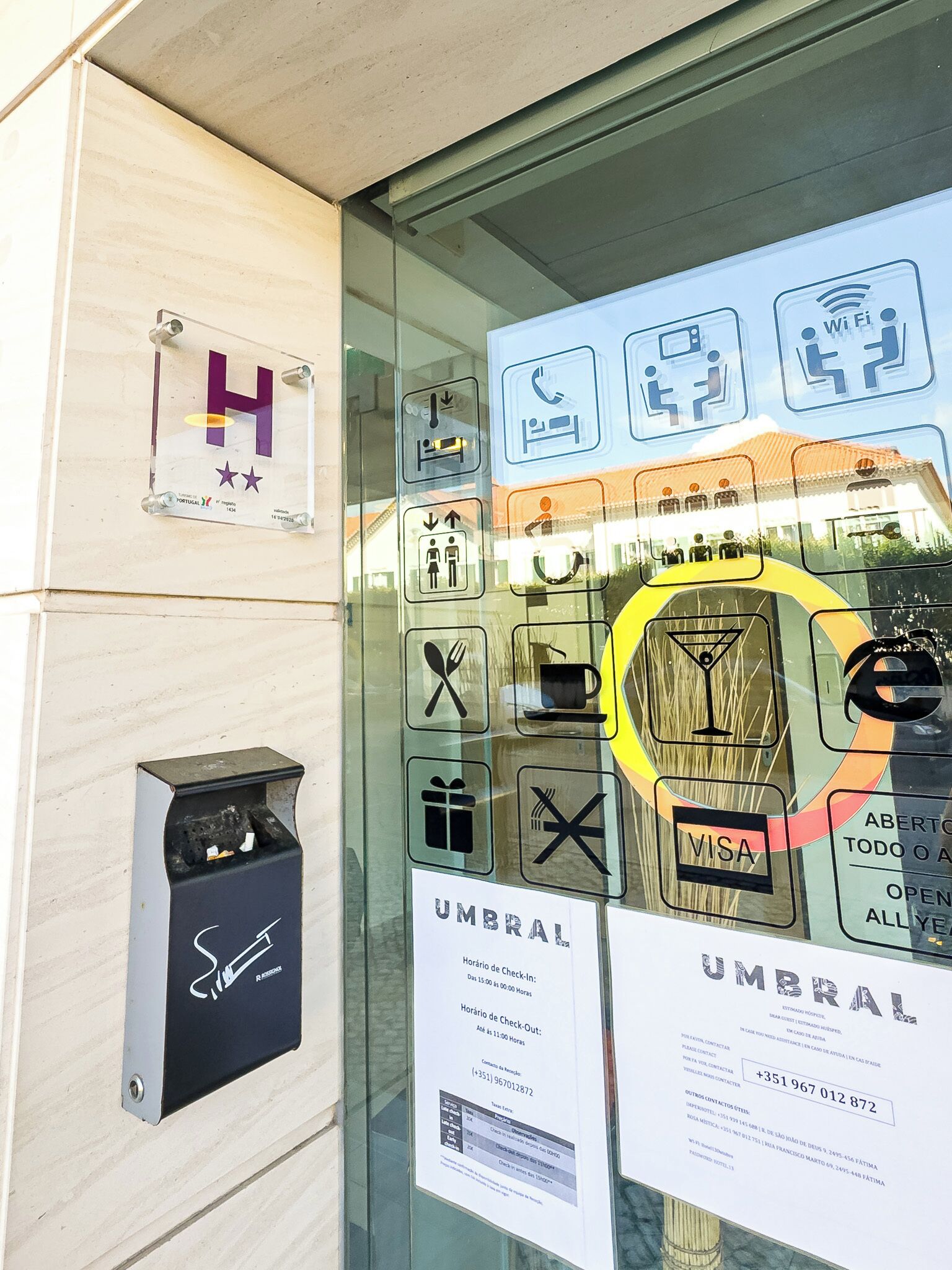 L'ingresso di un hotel con una porta in vetro che mostra diversi servizi e una reception.