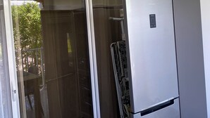 Uma cozinha moderna com geladeira de aço inoxidável, uma mesa de jantar de madeira e uma porta de vidro deslizante que dá para uma varanda.