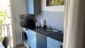 Cozinha moderna com máquina de lavar, pia e área de refeições com uma cadeira.