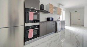 Een moderne keuken met roestvrijstalen apparatuur, houten kastjes en een marmeren vloer.