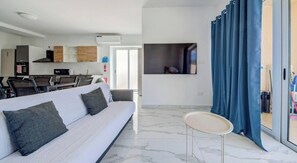 Een moderne woonkamer met een bank, een klein tafeltje en een aan de muur bevestigde televisie.
