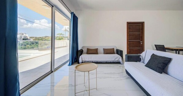 Een moderne kamer met een bed, een bank, een tafeltje en uitzicht op buiten.