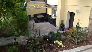 Ein Patio-Bereich mit Sitzgelegenheit, einer Wäscheleine und einem Garten mit verschiedenen Pflanzen.