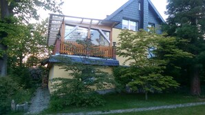 Ein zweistöckiges Haus mit Balkon, Holzzaun und Garten.