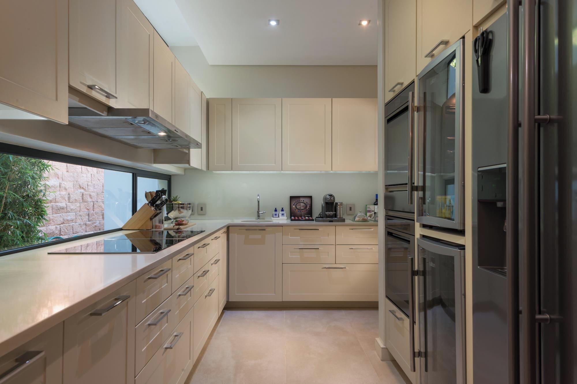 Een moderne keuken met roestvrijstalen apparatuur, een raam en uitzicht op groen.