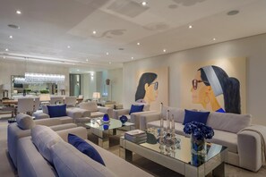 Ein modernes Wohnzimmer mit einem Glastisch, Sofas und einem Essbereich mit einer Pendelleuchte.