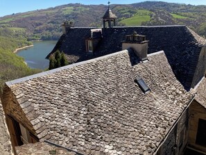 Un bâtiment dont le toit est fait de pierres, offrant une vue sur un lac et des collines.