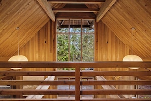A wooden interior with a large window, wooden beams, and hanging pendant lights. - Holzhutte - Mid-century alpine retreat - Hot tub (Government Camp)