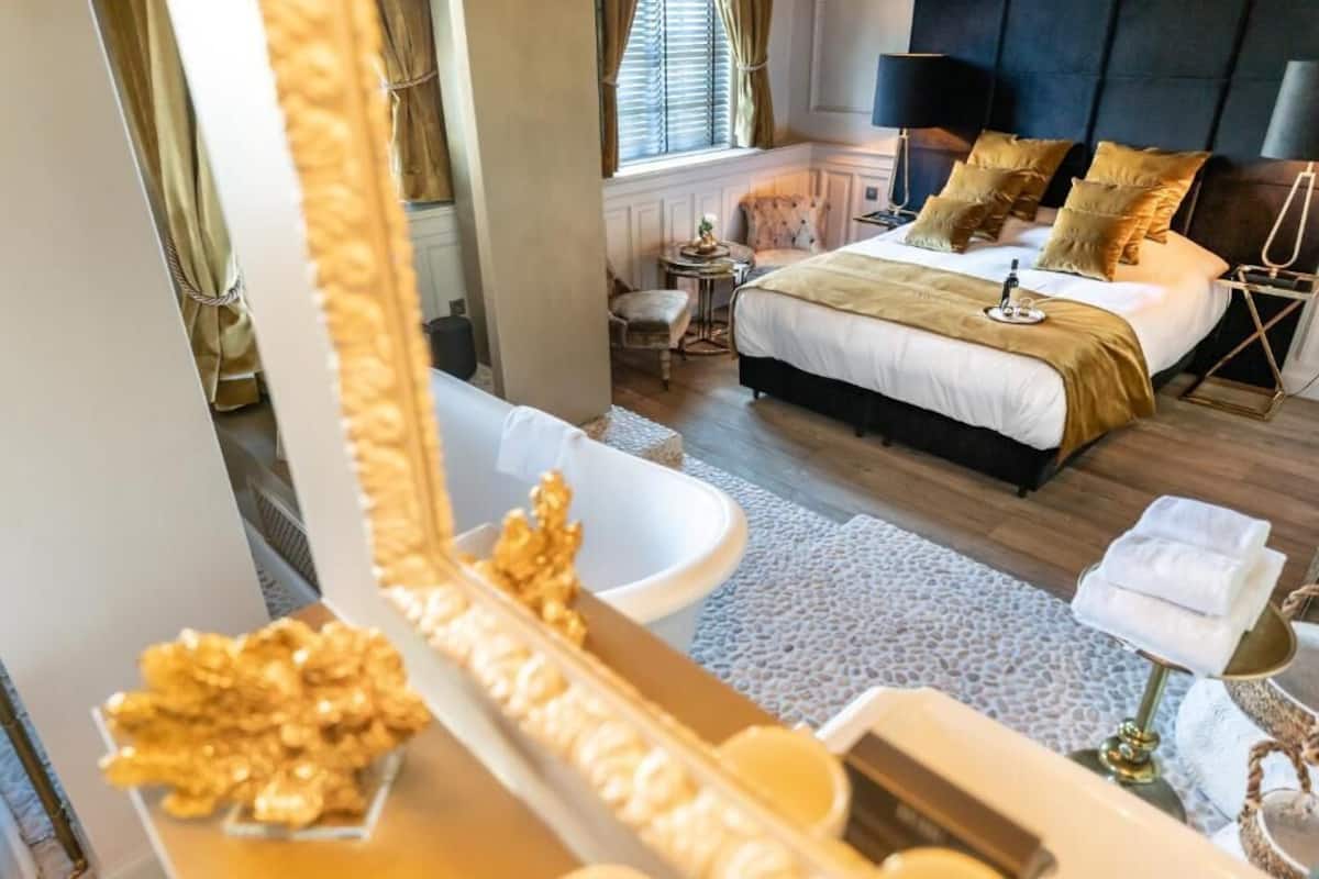 Une chambre avec un grand lit, des tables de chevet, un miroir et une vue sur l’extérieur.