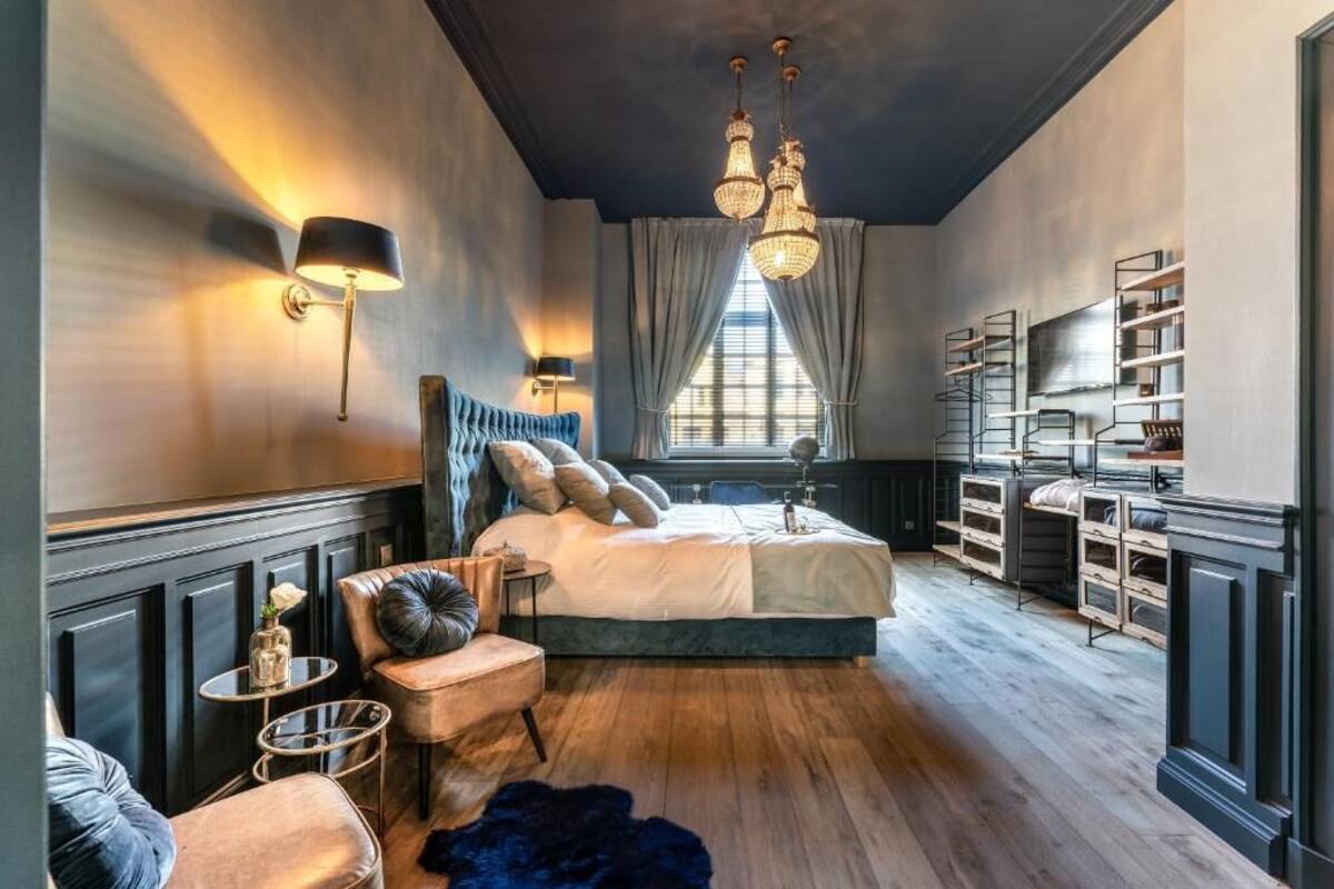 Une chambre à coucher avec un grand lit, des tables de chevet, une armoire et un lustre.