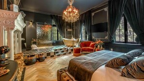Un dormitorio lujoso con una cama grande, una araña, un sillón rojo y un suelo a cuadros.