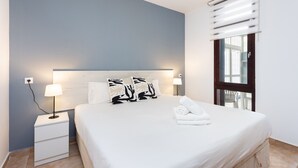 Una camera d'albergo con un letto, abat-jour, comodino, finestra con tende e vista esterna.