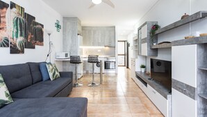 Una cucina moderna con isola centrale, zona pranzo con divano e sedie, e ventilatore a soffitto.