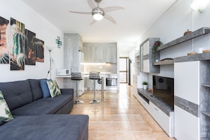 Eine moderne Küche mit einer zentralen Kochinsel, einem Essbereich mit einer Couch und Stühlen sowie einem Deckenventilator.