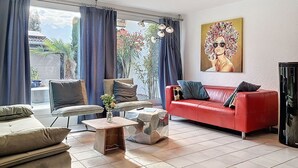 Un soggiorno con un divano rosso, un divano beige, un tavolino da caffè e un quadro appeso al muro.