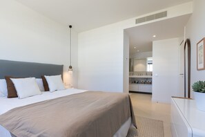 Habitación de hotel moderna con una cama grande, una mesita de noche, un espejo y vistas al baño contiguo.
