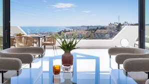 Un balcone con tavolo, sedie, un vaso di fiori e un bicchiere di bevanda.