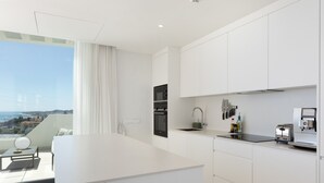 Una cucina moderna con mobili bianchi, forno, microonde, lavandino e macchina del caffè.