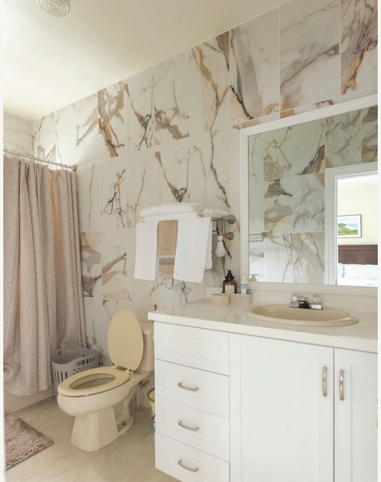 A bathroom with a toilet, sink, and mirror.
