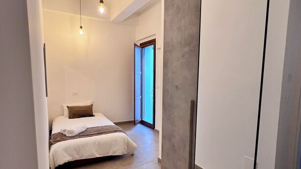 A modern bedroom with a bed, bedside lamps, and a large mirror. - Heart Of Eagle - Dwelling in the historic center with private courtyard (L'Aquila)