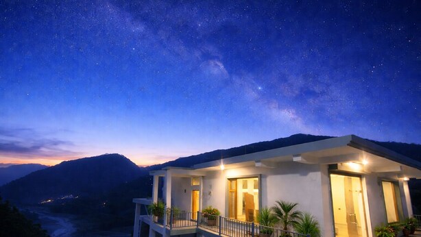 A modern house with a balcony, under a starry night sky.